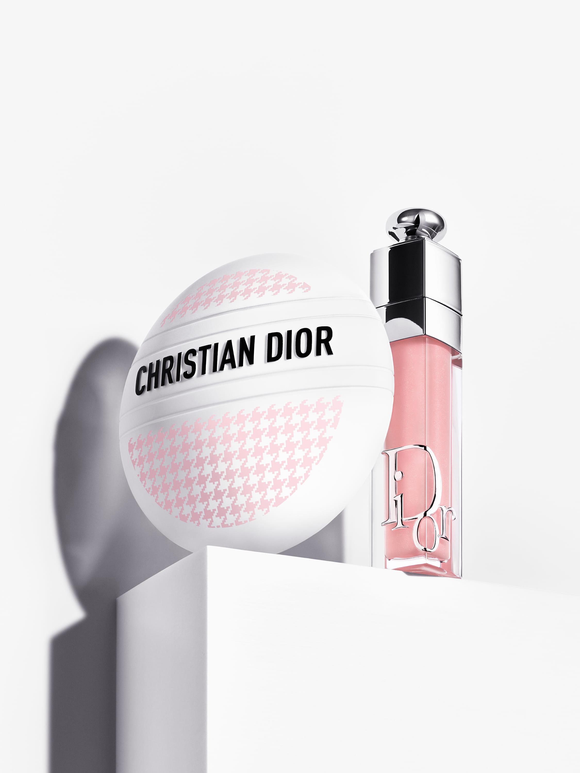 A photo on a neutral background of the limited edition of Dior Le Baume multi-purpose balm, with a pink houndstooth pattern matching a Dior mitzah.